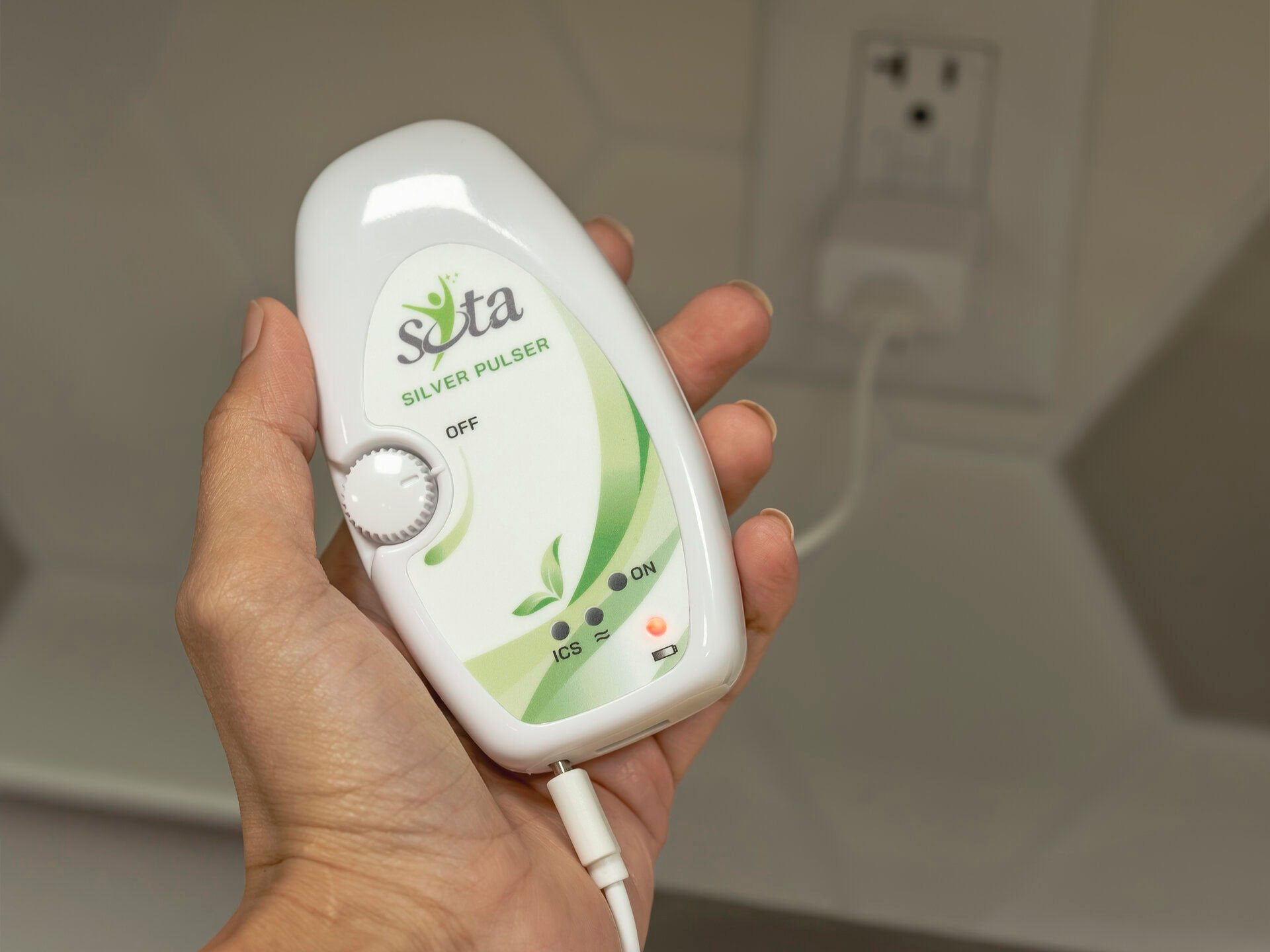 A hand holding the SOTA Silver Pulser unit